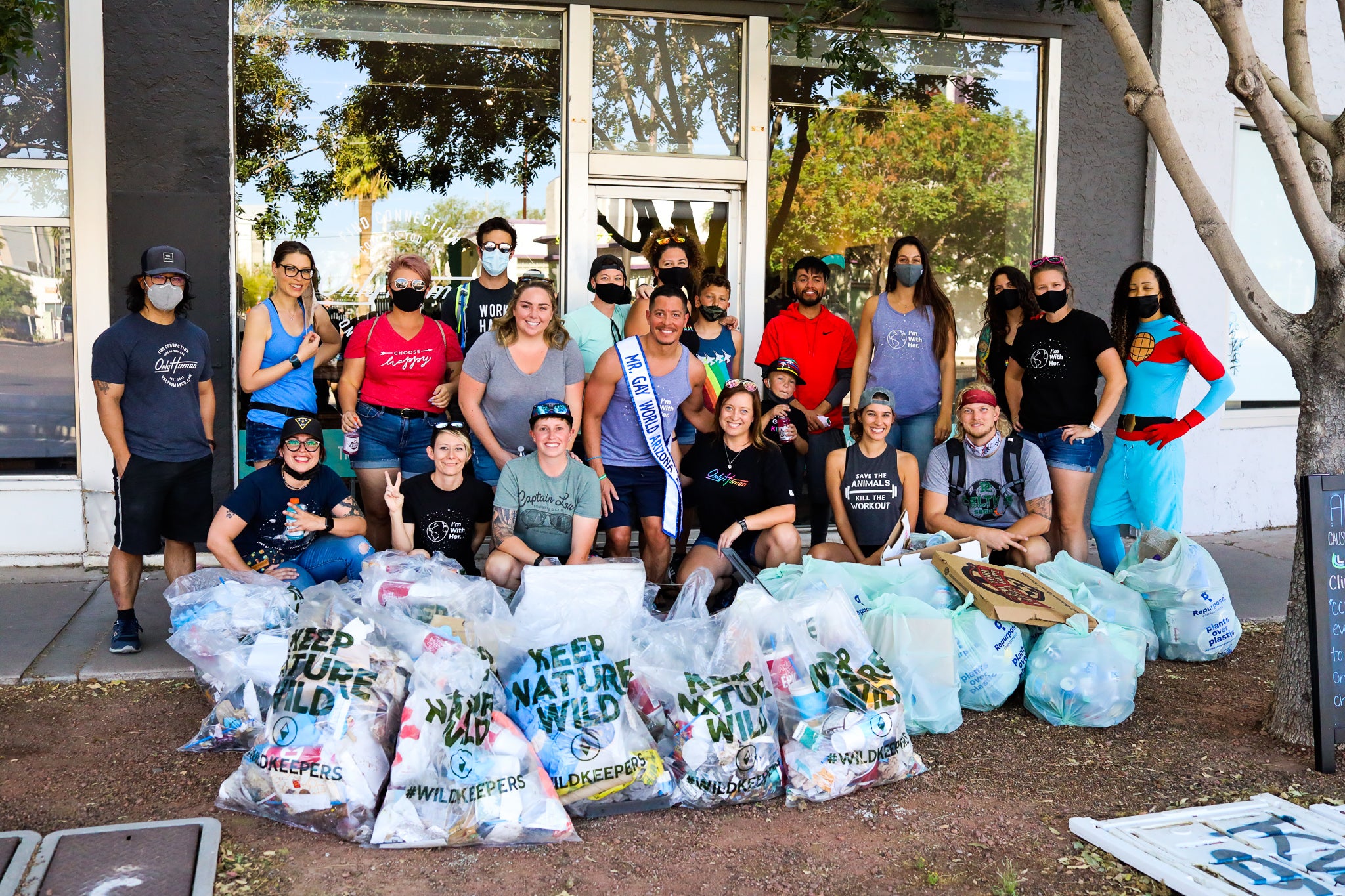 photo of large group of humans volunteering to pick up trash with a lot of trash bags in front of them
