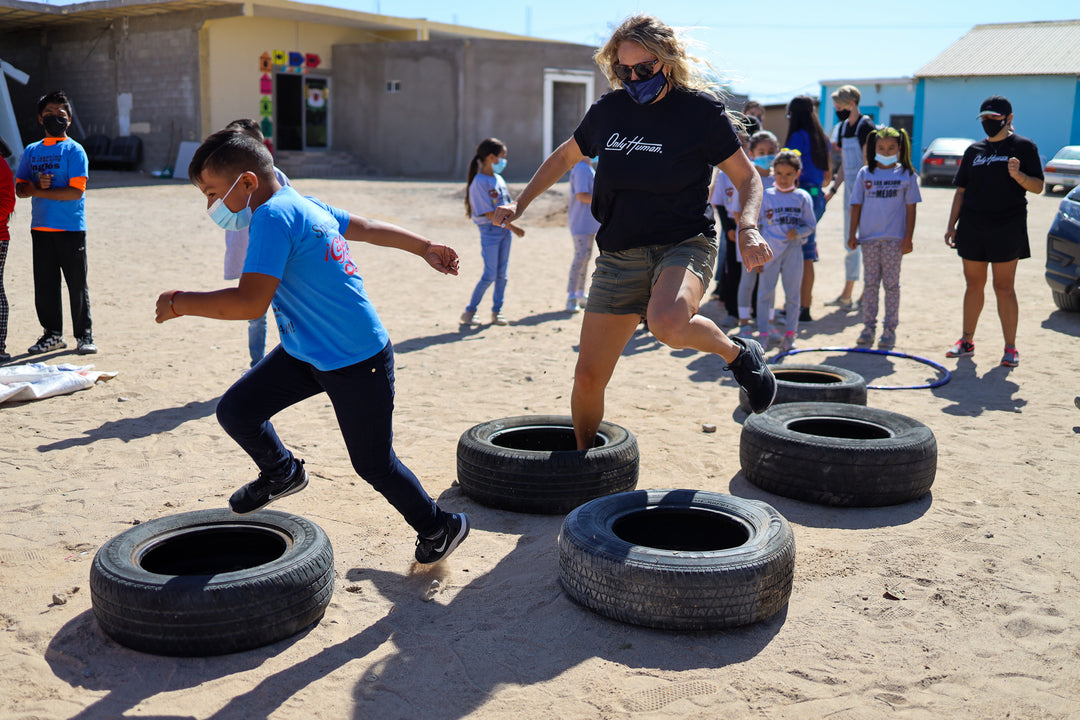 photo of only human volunteer jumping through tires with kid in mexico
