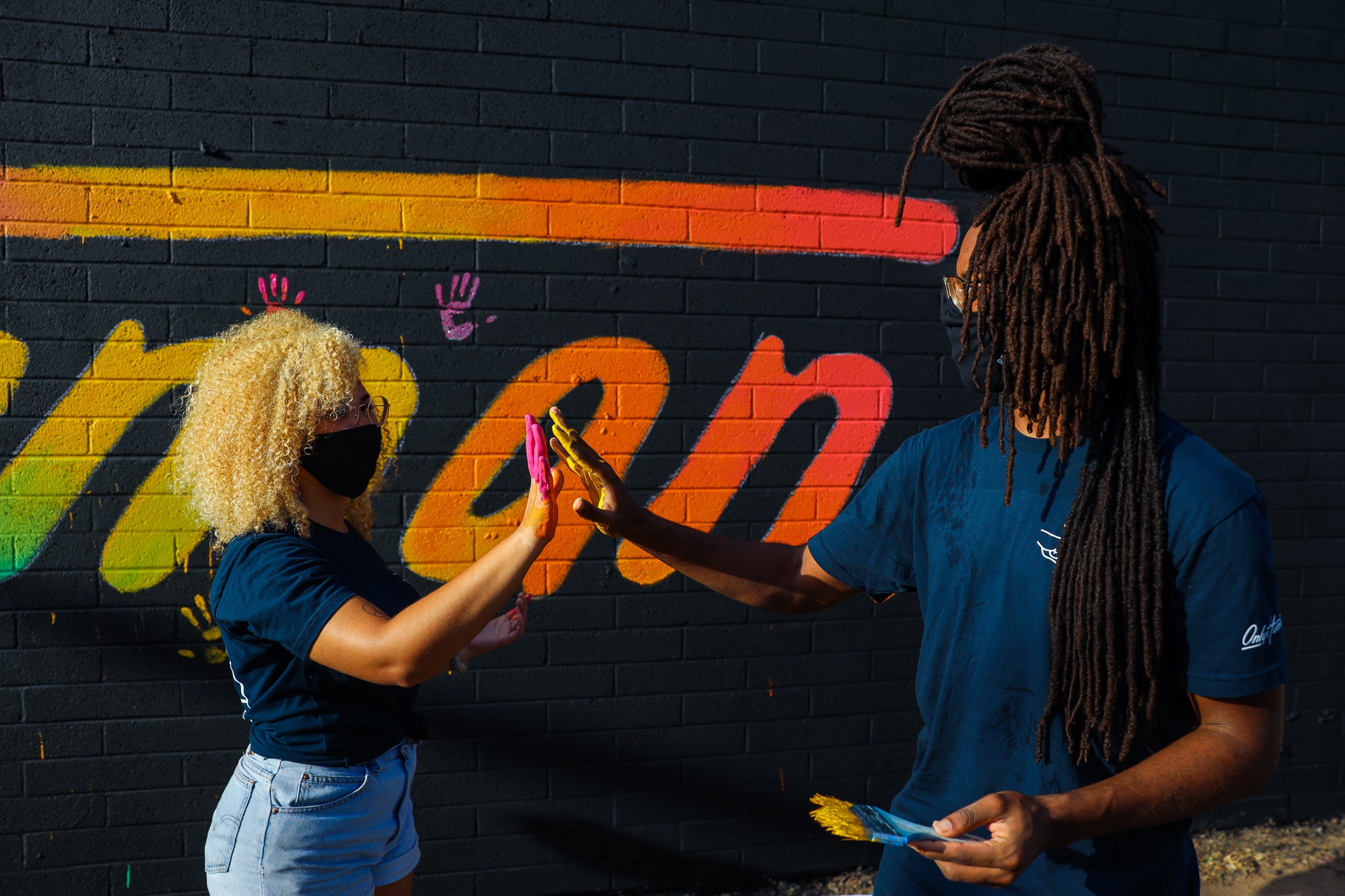photo of two humans high-fiving with paint on their hands