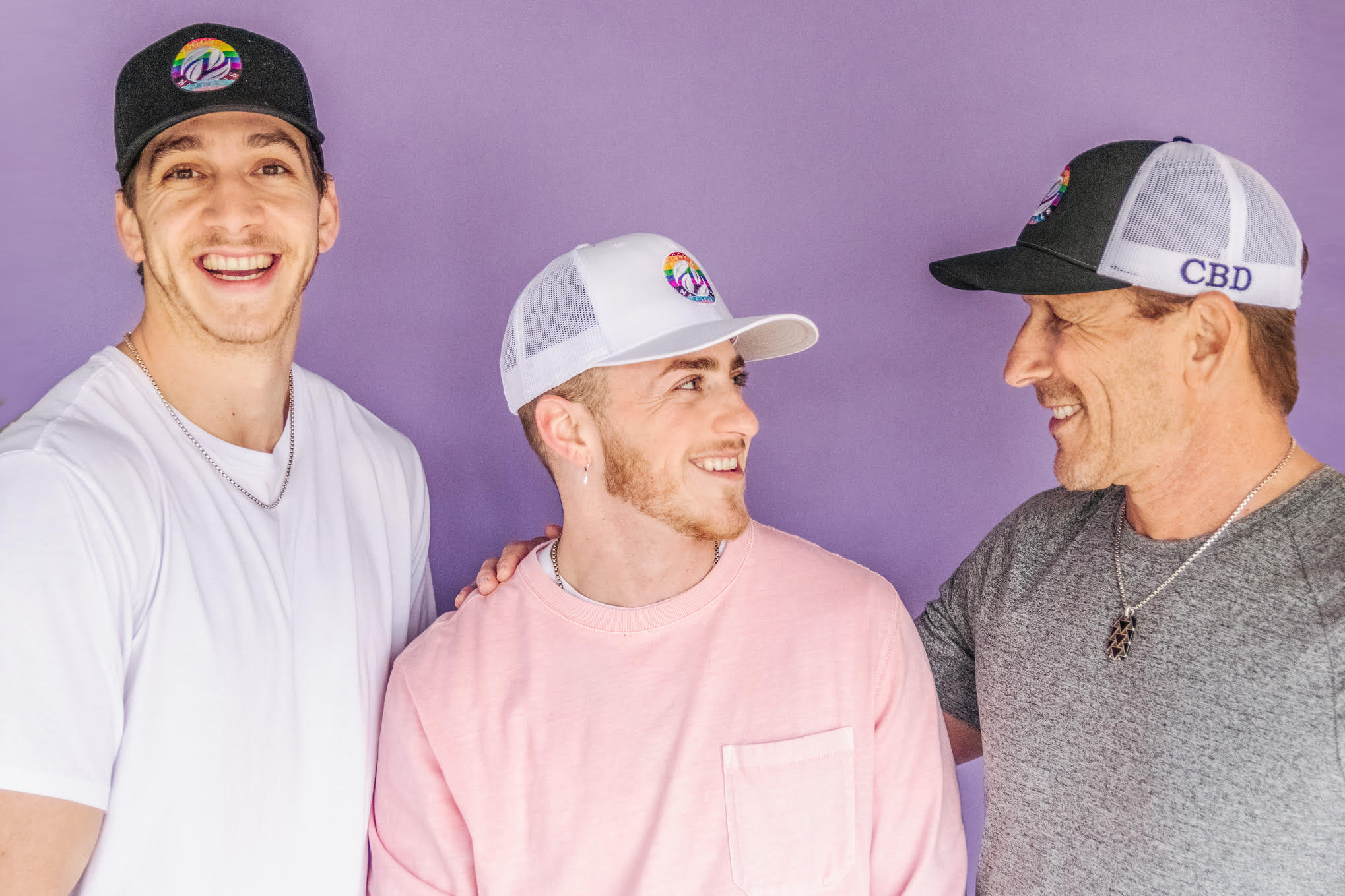 photo of 3 humans wearing hats and smiling at each other